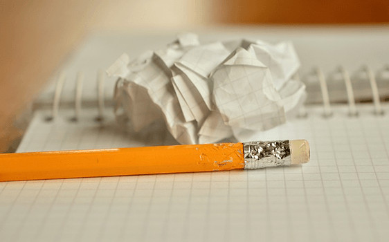 Crumpled paper and chewed pencil on top of graph paper notepad